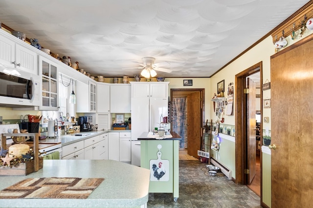 kitchen with ceiling fan, white microwave, white cabinets, a center island, and glass insert cabinets