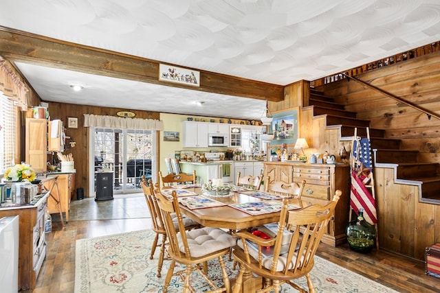 dining area featuring beamed ceiling, wood walls, and dark wood finished floors