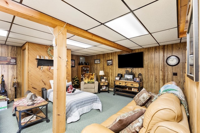 carpeted living room featuring a drop ceiling and wooden walls