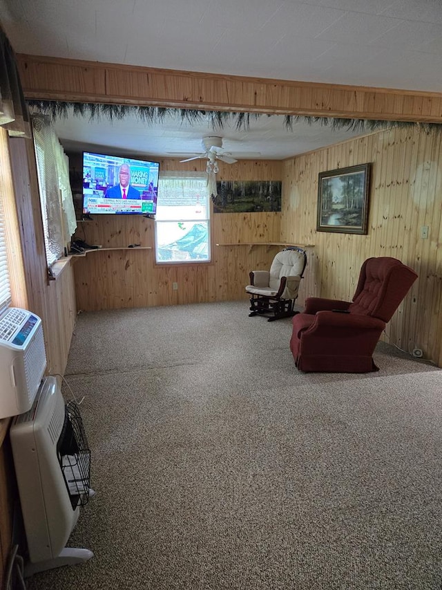 sitting room with carpet flooring, ceiling fan, and wood walls