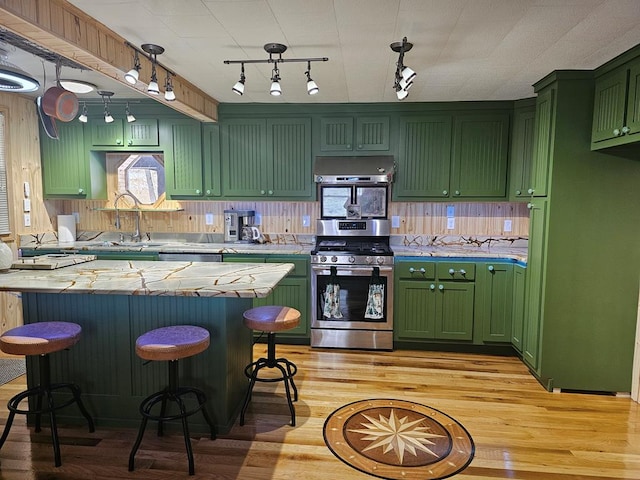 kitchen with sink, a breakfast bar area, green cabinetry, stainless steel appliances, and light hardwood / wood-style floors