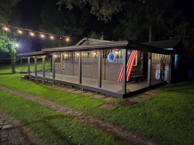 back house at night featuring a lawn