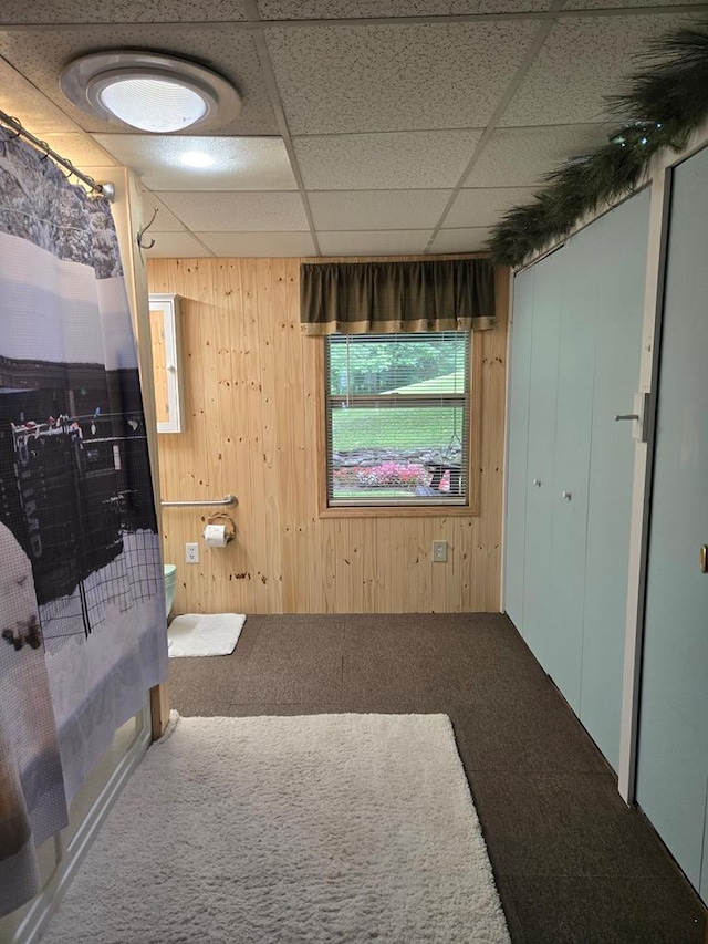 interior space with a paneled ceiling and wood walls