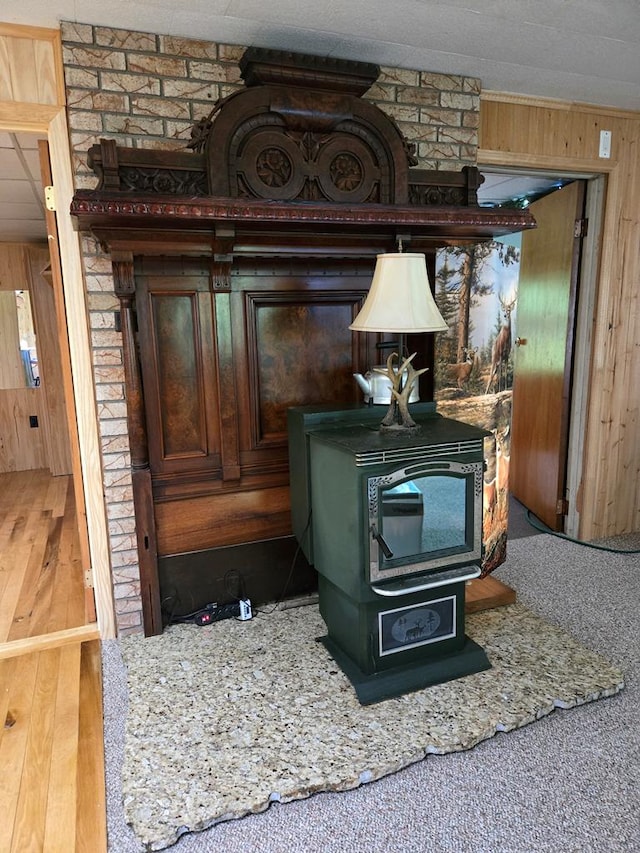 details featuring hardwood / wood-style flooring, wooden walls, and a wood stove