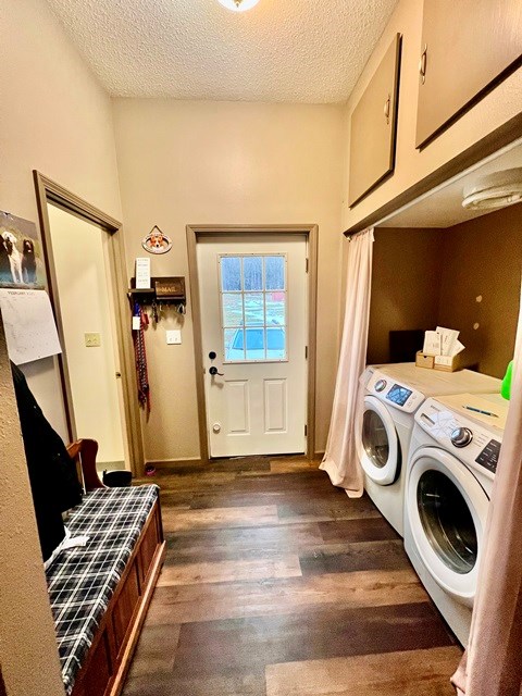 washroom with dark wood-style flooring, cabinet space, a textured ceiling, washer and dryer, and baseboards