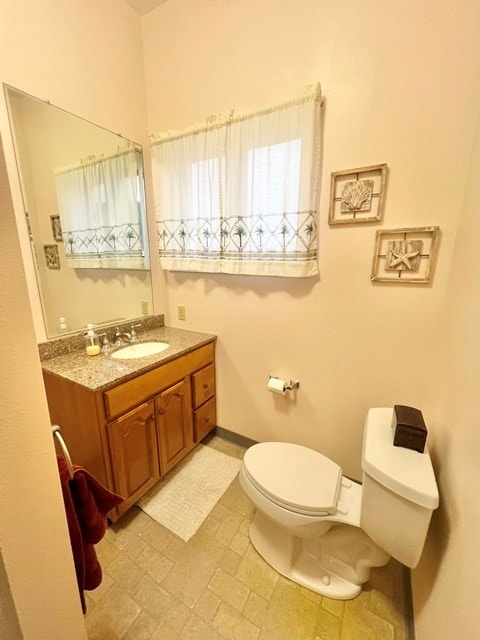 bathroom featuring baseboards, vanity, and toilet