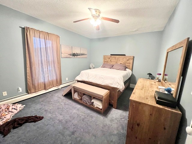 bedroom featuring carpet, a textured ceiling, baseboard heating, and a ceiling fan