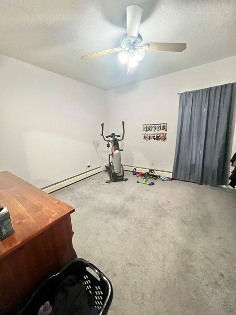 exercise area with a ceiling fan, a baseboard radiator, and a textured ceiling