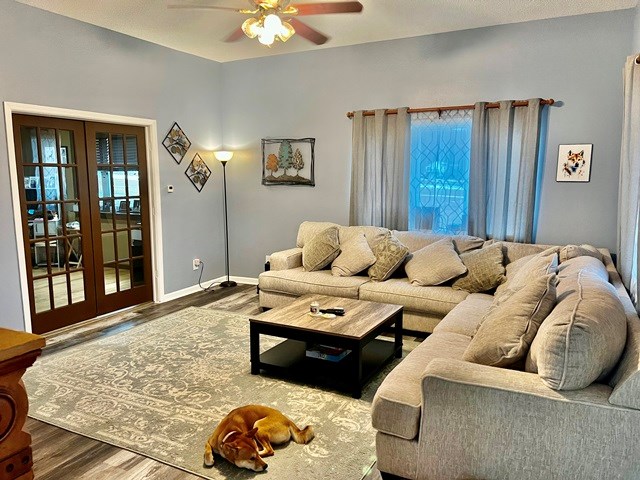 living room with french doors, ceiling fan, baseboards, and wood finished floors