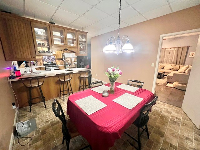 dining space featuring a drop ceiling and a notable chandelier