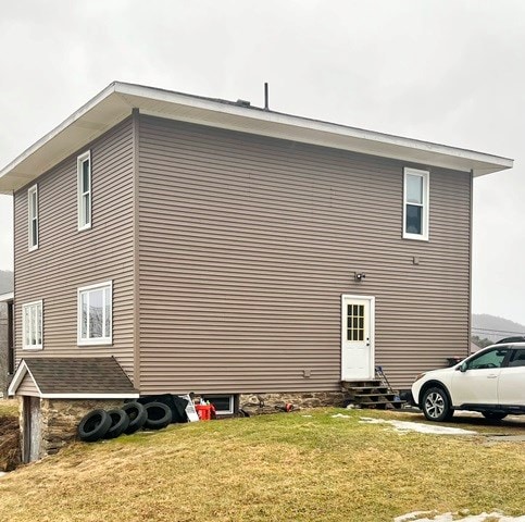 view of property exterior with entry steps and a lawn