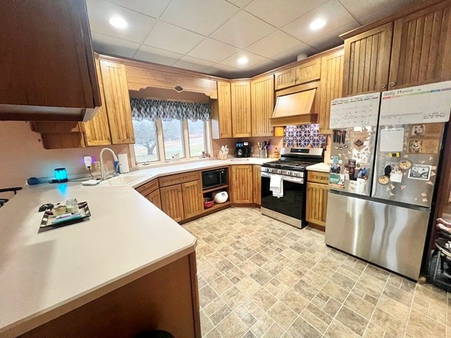 kitchen featuring recessed lighting, stainless steel appliances, a sink, light countertops, and wall chimney range hood