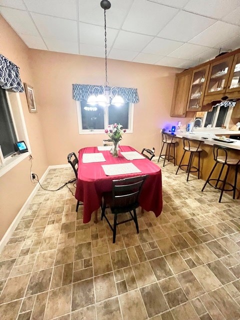 dining room featuring a drop ceiling and baseboards