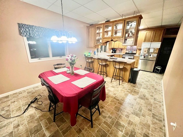 dining space featuring a drop ceiling and baseboards