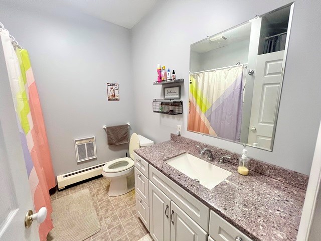 full bathroom with a shower with curtain, toilet, vanity, and baseboard heating