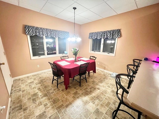 dining space featuring a chandelier, a paneled ceiling, and baseboards