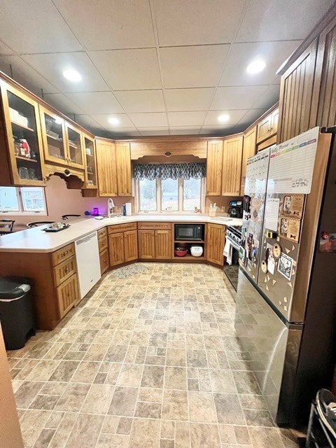 kitchen with glass insert cabinets, appliances with stainless steel finishes, light countertops, and a sink