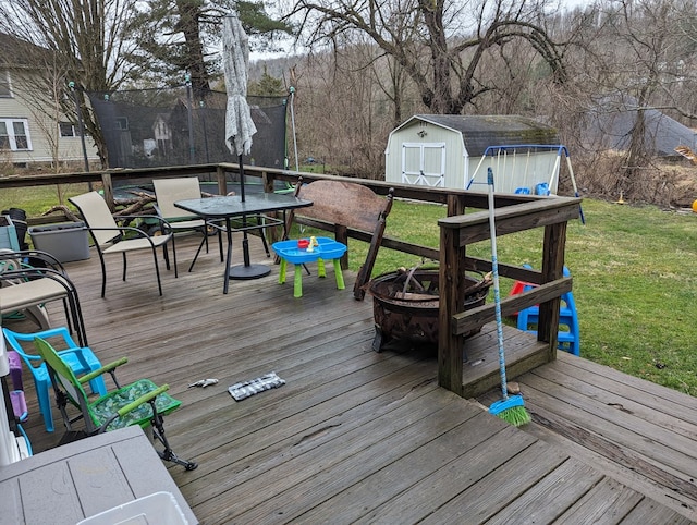 deck with a storage shed, a yard, and a trampoline