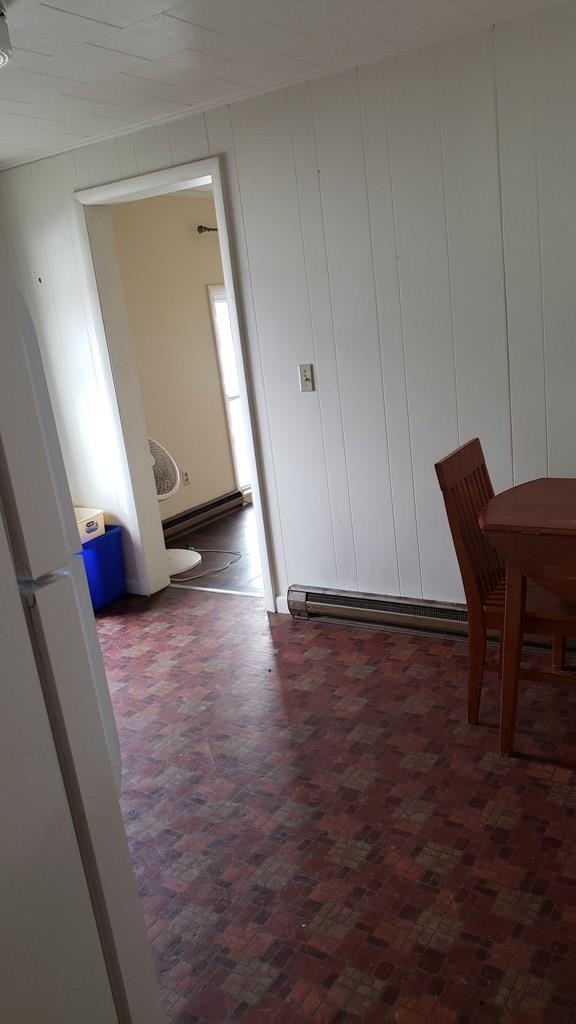 hallway with a baseboard radiator and wood walls