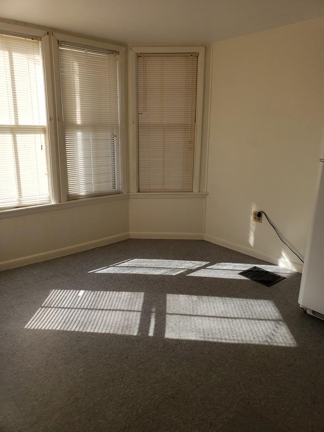 unfurnished room featuring dark carpet