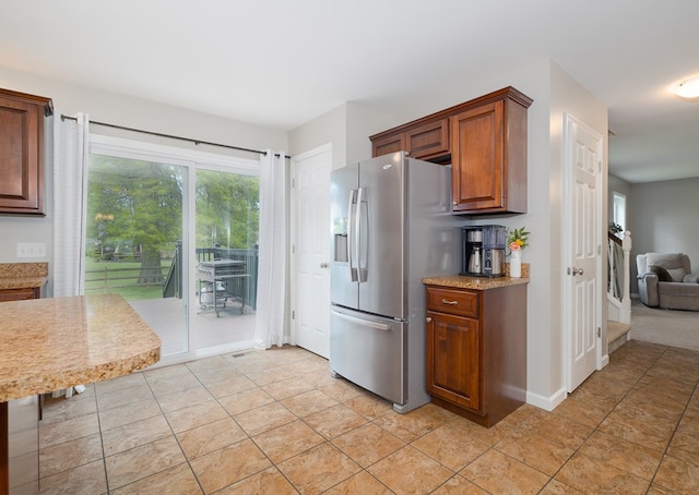 113 W Woodlawn Ave, Elkland, PA 16920 - kitchen with stainless steel refrigerator with ice dispenser, light tile patterned flooring, brown cabinets, and light stone counters