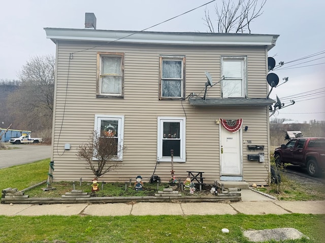 view of front facade featuring entry steps and a chimney