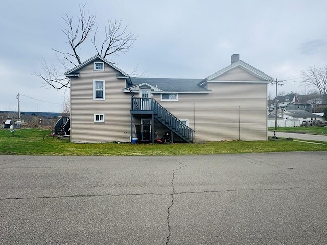 rear view of property with stairs, a yard, and a chimney