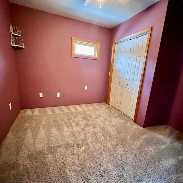 unfurnished bedroom featuring carpet, a closet, and ceiling fan