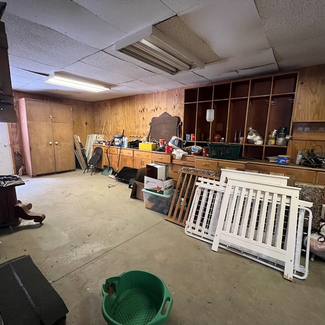 interior space with a drop ceiling and wood walls