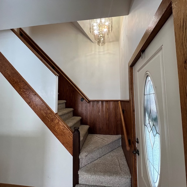 foyer entrance with an inviting chandelier and wood walls