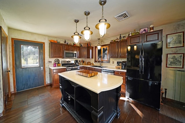 kitchen featuring hanging light fixtures, sink, appliances with stainless steel finishes, a kitchen island, and dark hardwood / wood-style flooring