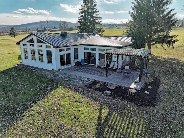 back of house with a lawn, a mountain view, a rural view, and a patio area