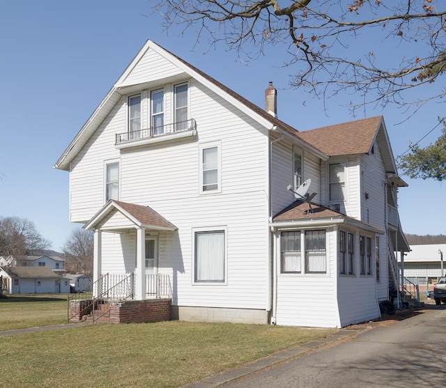 view of front of property featuring a balcony and a front yard