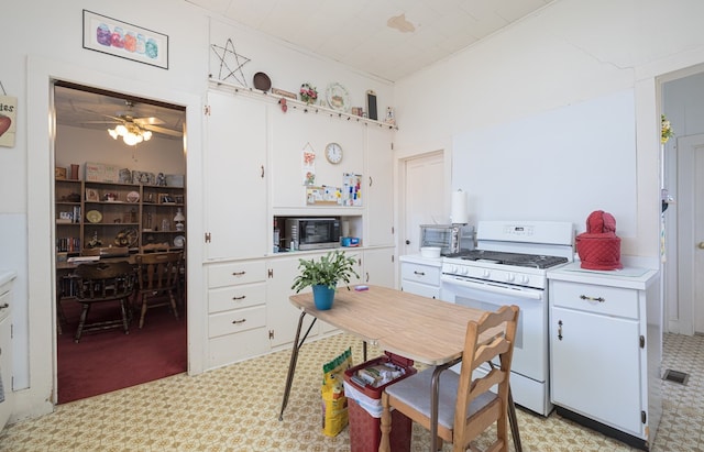 kitchen with white cabinets, light colored carpet, ceiling fan, and white gas stove