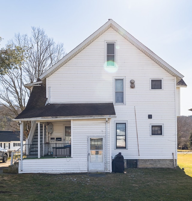 rear view of property featuring a yard and a porch