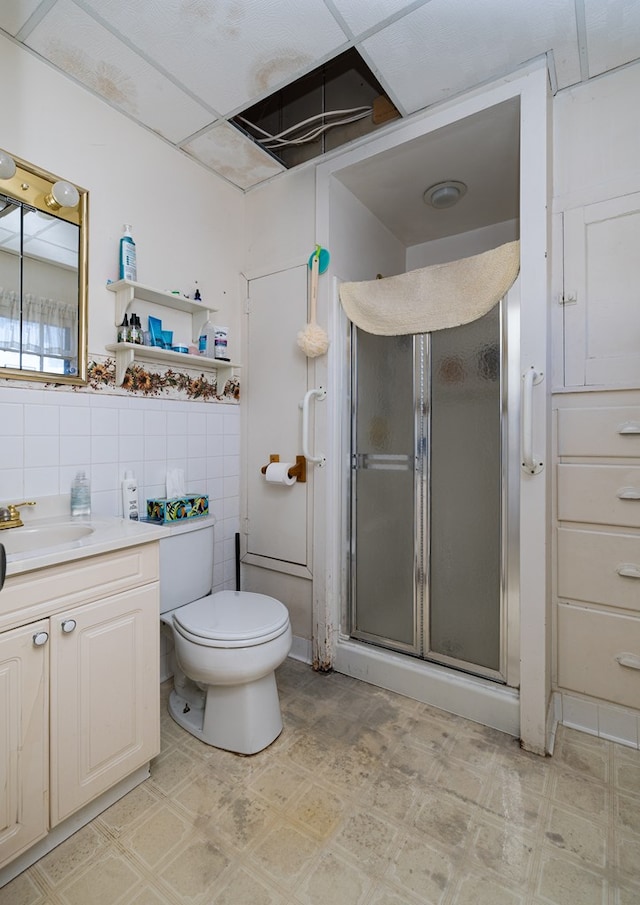 bathroom featuring vanity, a shower with shower door, tile walls, and toilet