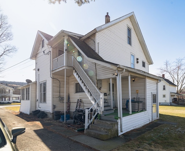 exterior space with covered porch, a balcony, and a lawn