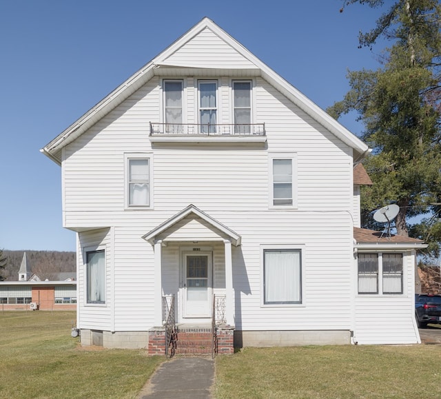 view of front of property featuring a balcony and a front yard