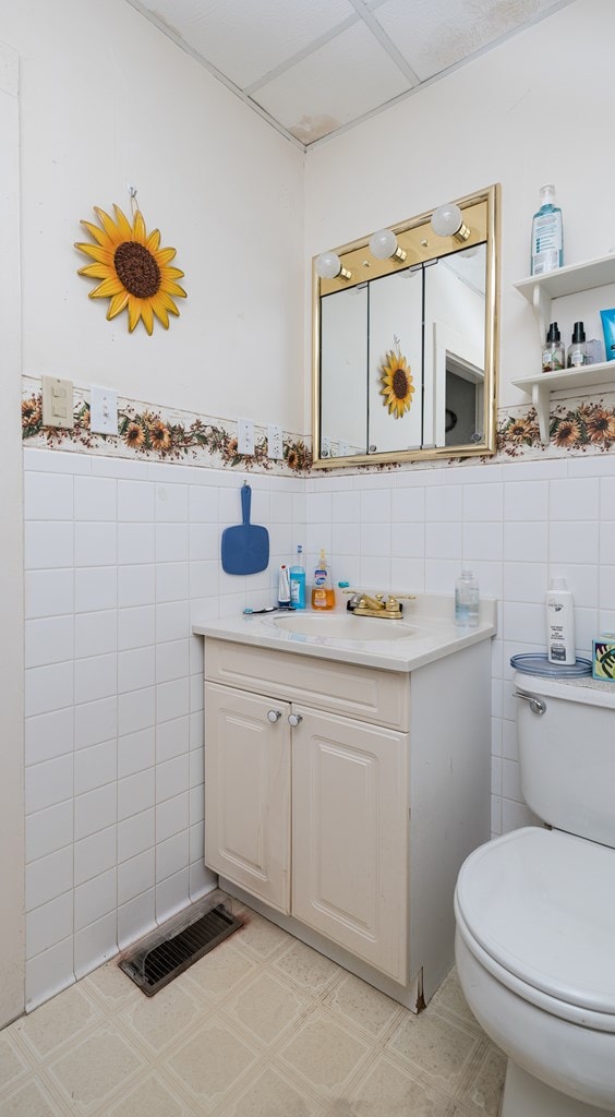 bathroom featuring vanity, toilet, and tile walls