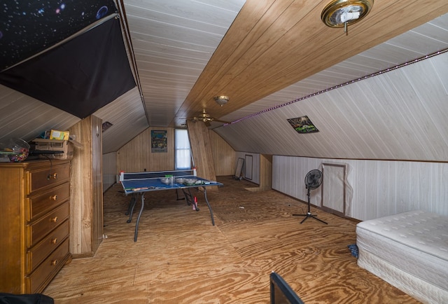 game room featuring vaulted ceiling and wooden walls