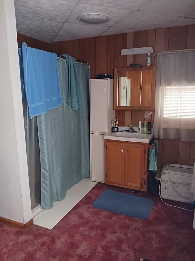 kitchen with wooden walls, carpet flooring, sink, and white fridge