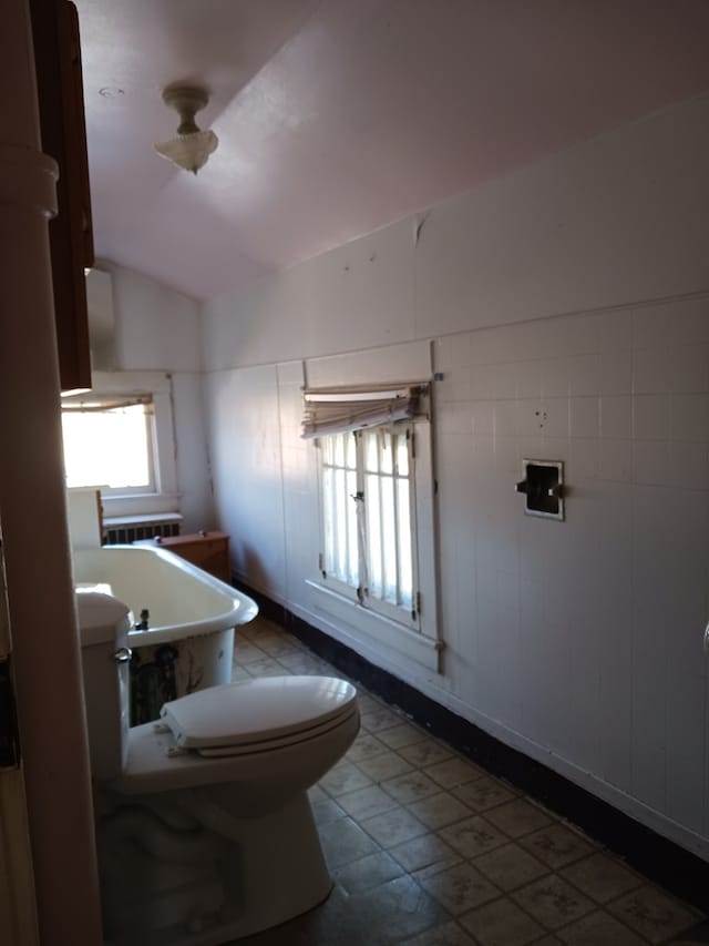 bathroom with lofted ceiling, radiator heating unit, and toilet