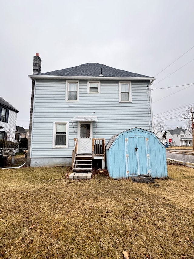 rear view of house with an outdoor structure, fence, a lawn, a shed, and a chimney