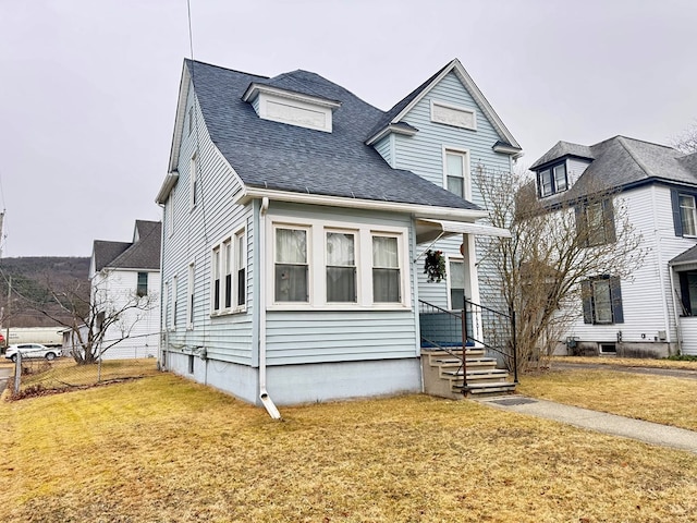 view of front of property with a shingled roof, a front yard, and fence