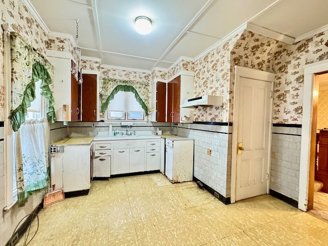 kitchen with wallpapered walls, under cabinet range hood, light floors, and wainscoting