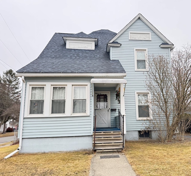 view of front of property featuring a shingled roof and a front yard