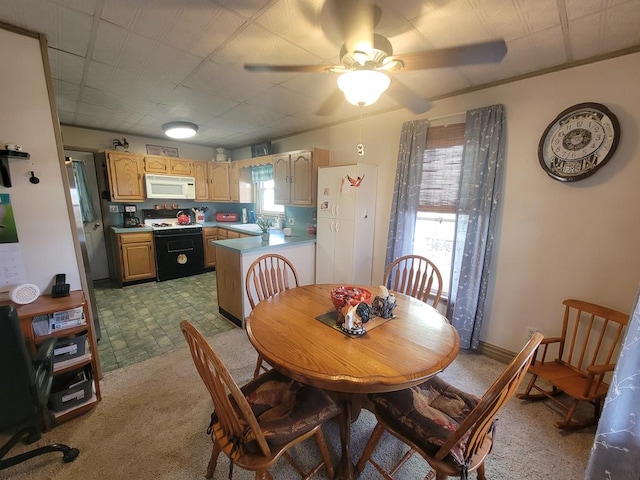 dining area featuring light carpet, sink, and ceiling fan