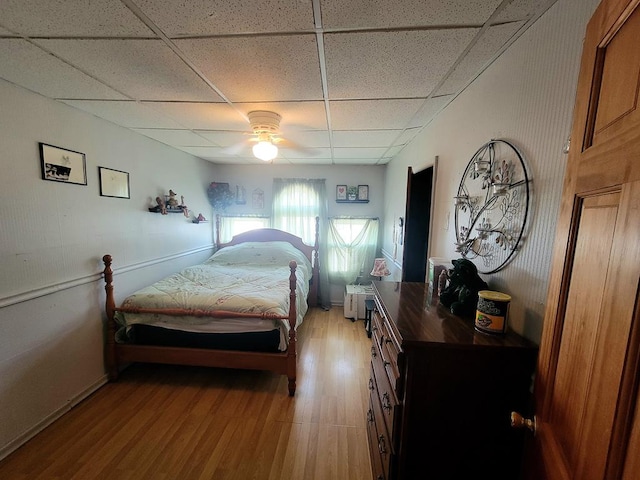 bedroom with ceiling fan, a paneled ceiling, and light wood-type flooring