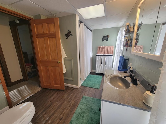 bathroom with a drop ceiling, vanity, decorative backsplash, and wood-type flooring