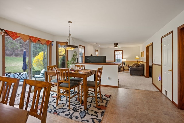 carpeted dining room with ceiling fan and baseboards